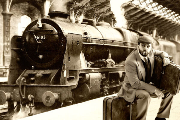 Man sitting on his suitcase while waiting at the train station