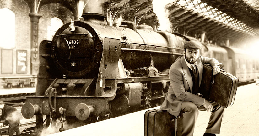 Man sitting on his suitcase while waiting at the train station