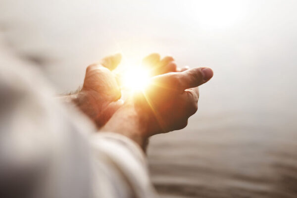 Spiritual image of a man holding hope and light in his palms with a blurred background