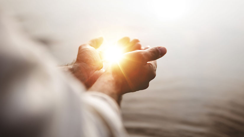 Spiritual image of a man holding hope and light in his palms with a blurred background