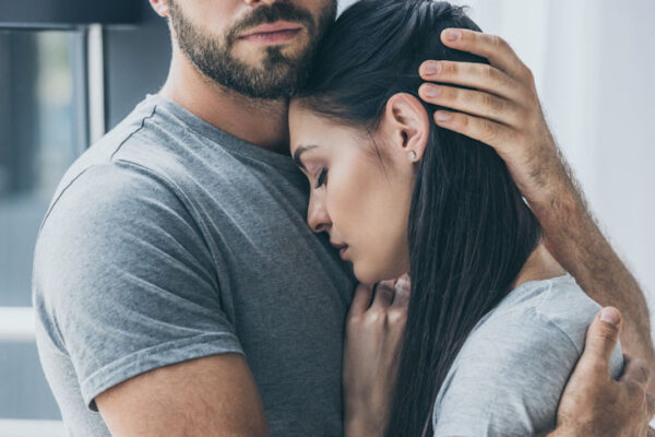 Cropped shot of bearded man hugging and supporting young sad woman