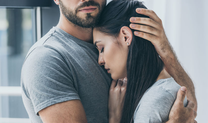 Cropped shot of bearded man hugging and supporting young sad woman