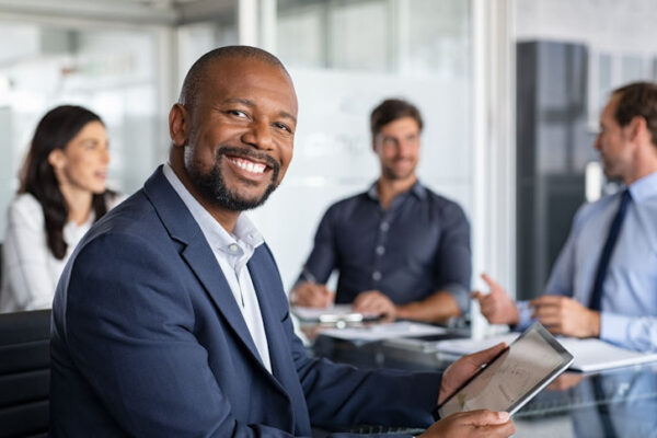 Business man smiling with his team working in the background