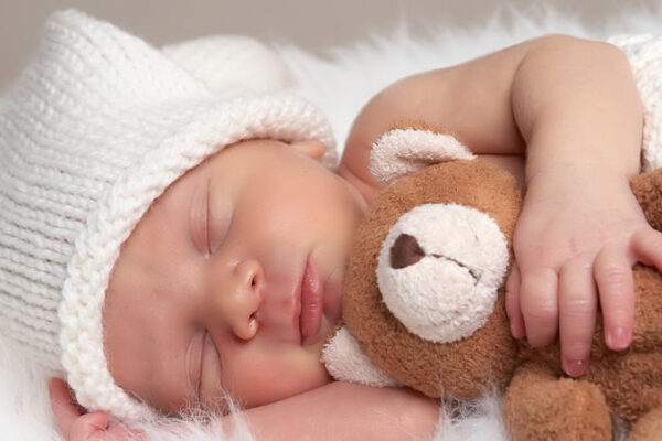 sleeping newborn baby hugging a teddy bear