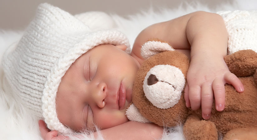 sleeping newborn baby hugging a teddy bear