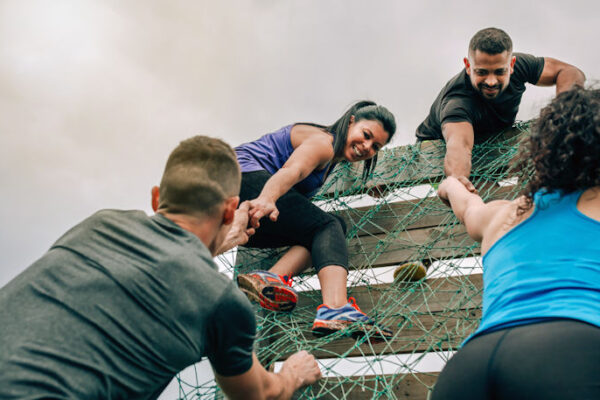 Overcoming challenges - a group of participants in an obstacle course climbing a net